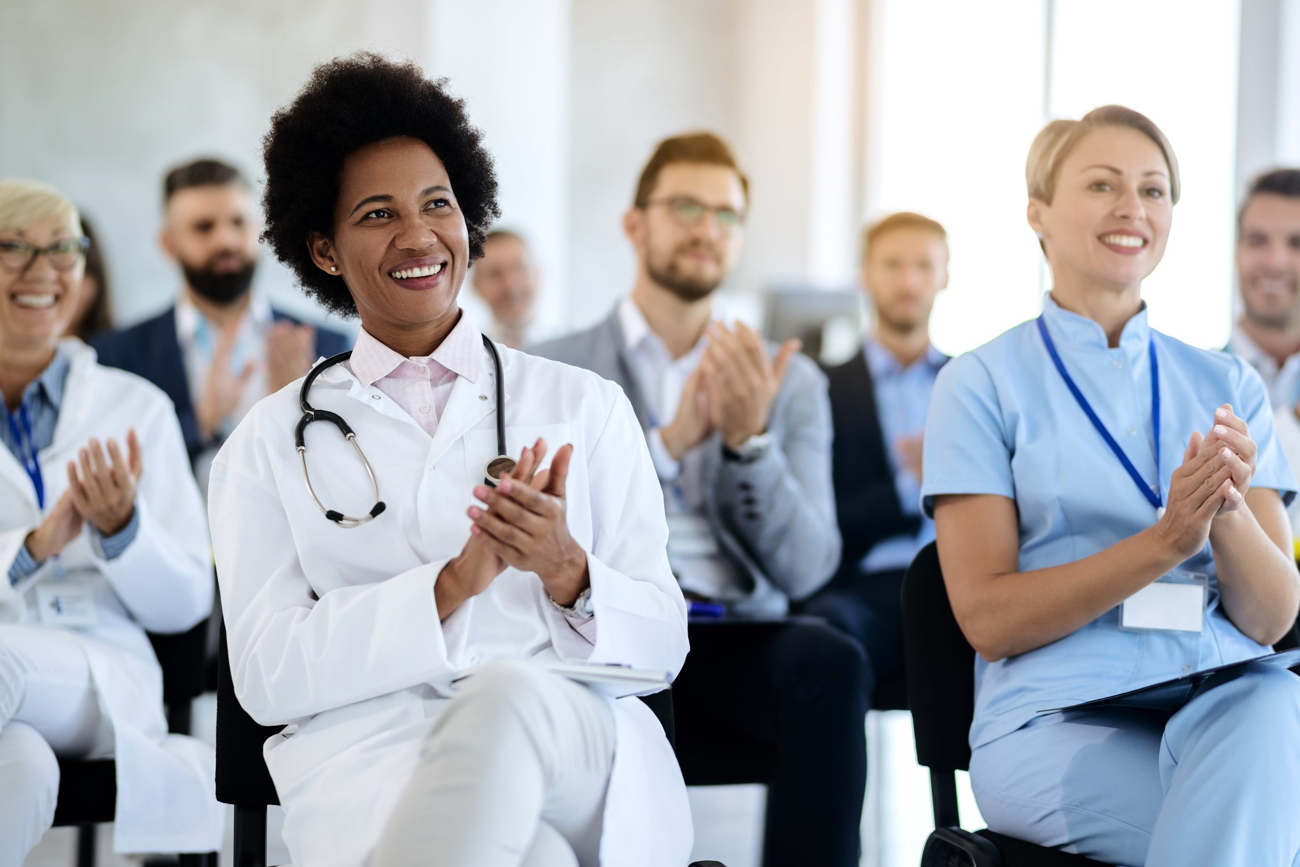 happy-african-american-doctor-applauding-while-attending-healthcare-seminar-min